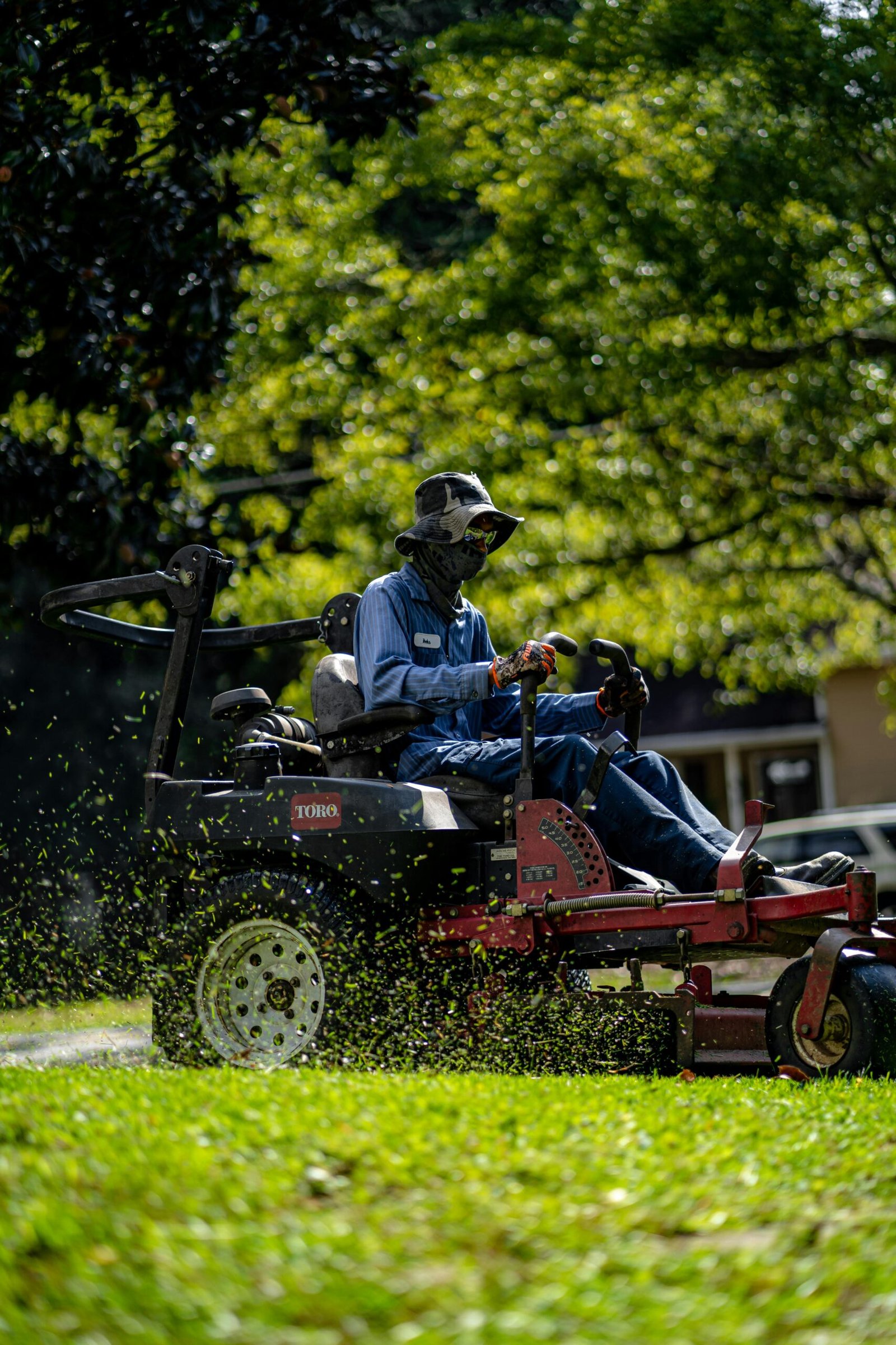 A VV Landscaping Company staff member operating a commercial ride-on mower across a lush green lawn in Las Vegas, delivering professional grass cutting and lawn maintenance services
